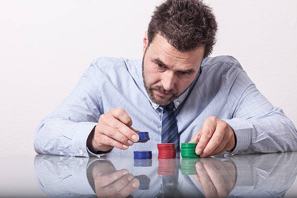 istock Mature man with poker chips on glass table, sorting stacks 487465056