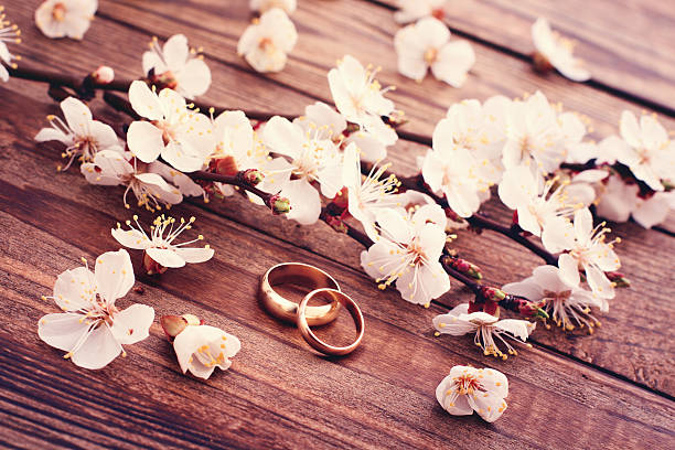 istock Wedding rings. Flowering branch flowers on wooden surface. 487465681