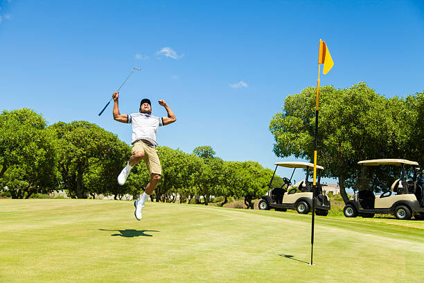 Golfers playing golf in a spectacular environment surrounded by lake and with luxury properties in the background. Luxury golf course on a summer day in Spain.