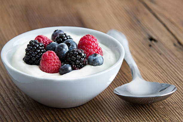 Bowl of fresh mixed berries and yogurt Bowl of fresh mixed berries and yogurt with farm fresh strawberries, blackberries and blueberries served on a wooden table yogurt photos stock pictures, royalty-free photos & images