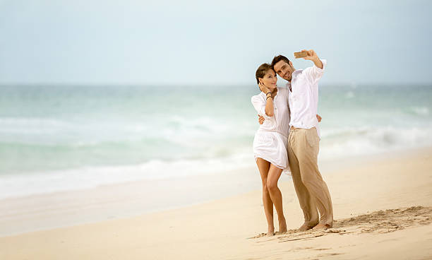 istock Beach vacation couple taking selfie photograph using smartphone 487468534
