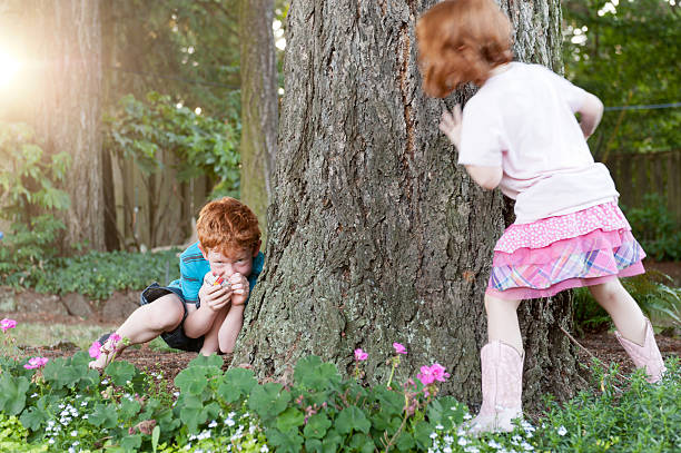 Siblings play hide and seek in backyard stock photo