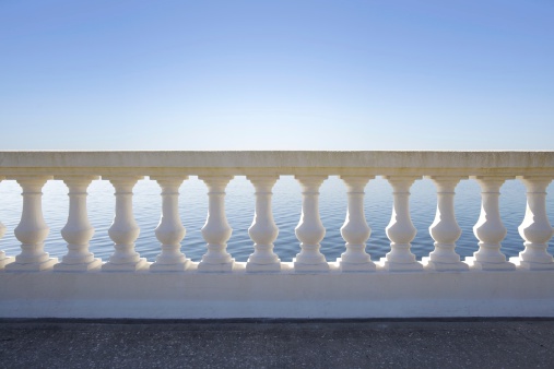A beautiful balustrade basked in early morning sun with the sea visible beyond.