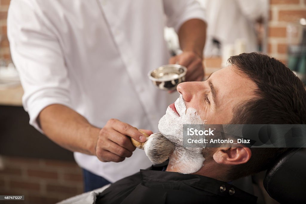 Ready for a shave at the barber's Barber putting some shaving cream on a client before shaving his beard in a barber shop 20-29 Years Stock Photo