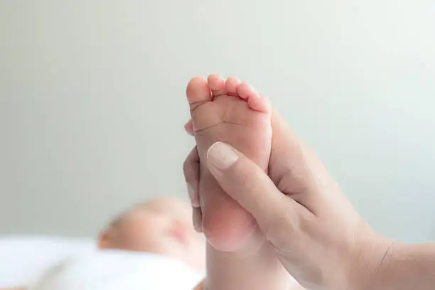 Mother doing foot massage to cute baby.