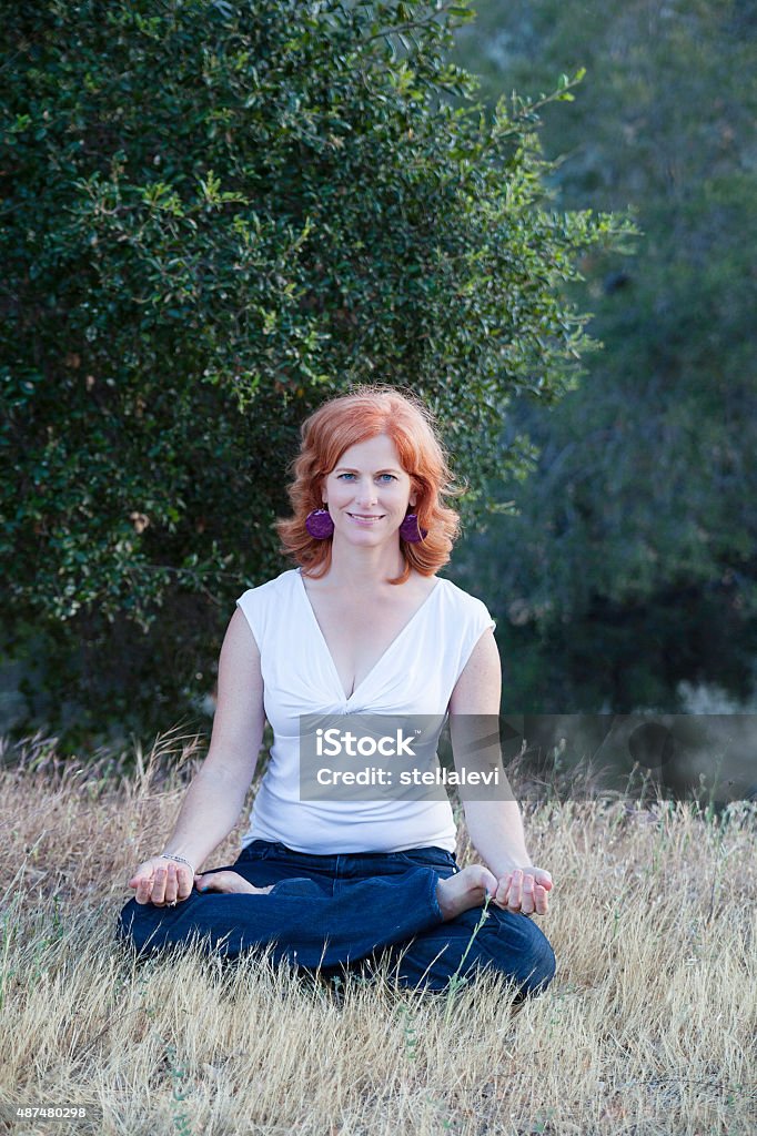 Beautiful woman meditating in nature Beautiful woman meditating in nature sitting in a lotus position. 2015 Stock Photo