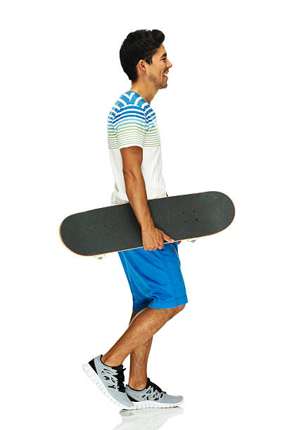 istock Smiling man walking and holding skateboard 487488335