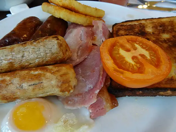 Photo showing a fried breakfast consisting of bacon, toast, hash browns, a fried egg and a mixture of both pork and vegetarian sausages.