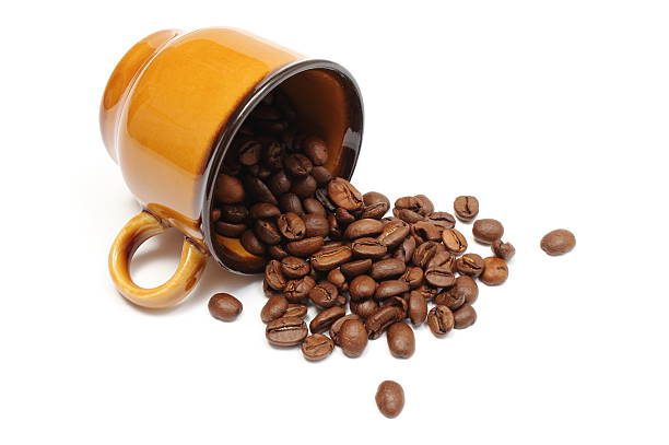 Overturned coffee cup and heap of coffee grains, coffee beans. Isolated on white background