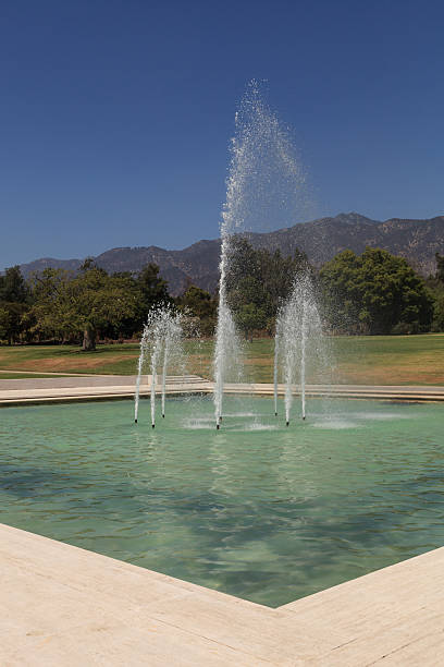 Fountain with mountains in the background Blue spraying fountain of water with the mountains in the background at Los Angeles Arboretum gardens in California, United States, August 2015 – Editorial use only arboretum stock pictures, royalty-free photos & images