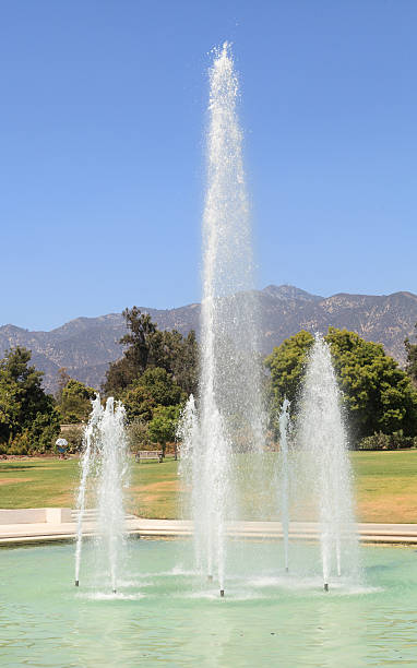 fountain with mountains in the background Blue spraying fountain of water with the mountains in the background at Los Angeles Arboretum gardens in California, United States, August 2015 – Editorial use only arboretum stock pictures, royalty-free photos & images