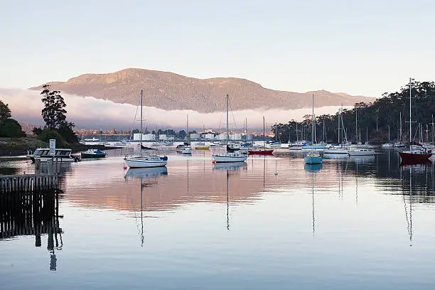 Unusual fog bank drifts down the Derwent River, Hobart, Tasmania, with Mount Wellington in background and Geilston Bay yacht harbour in foreground