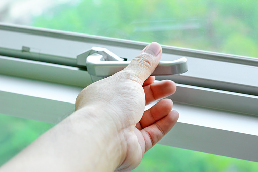 Hand holding glass window latch handle
