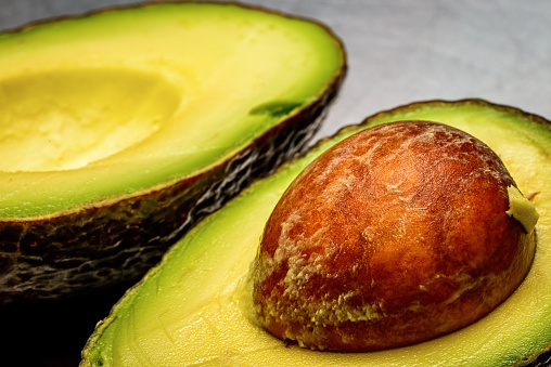 Cut open avocado in the fresh state, revealing the texture of a large single seed structure. This fruit is loaded with important nutrients to support health.