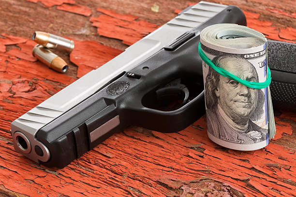 istock Gun with a roll of 100 dollar banknotes 487510815