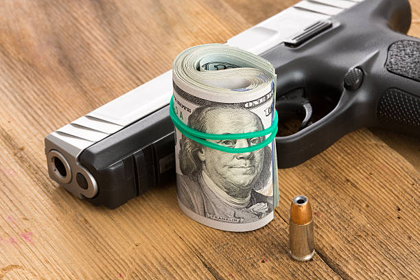 istock Handgun with a roll of dollar bills and a bullet 487511857