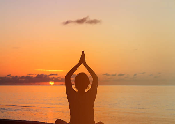 istock Silhouette of young man doing yoga at sunset 487514578