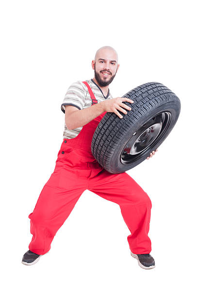 istock Smiling mechanic lifting a heavy car wheel 487516218