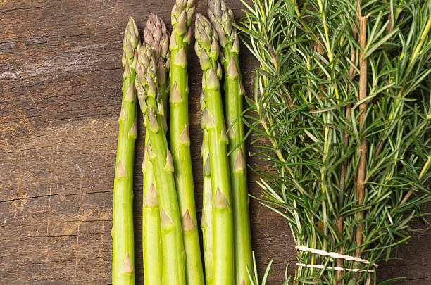 asparagus and bundle of rosemary on wood closeup