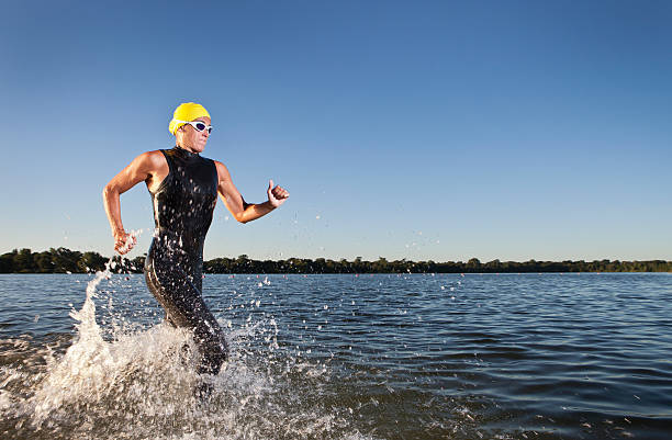 triatlón participante corriendo en el agua. - triathlete fotografías e imágenes de stock
