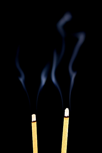 Burning incense sticks isolated against a black background