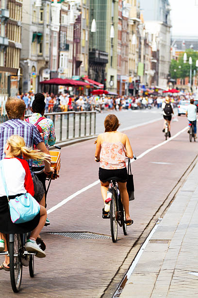 cycling personen in street damrak - editorial outdoors vertical amsterdam stock-fotos und bilder