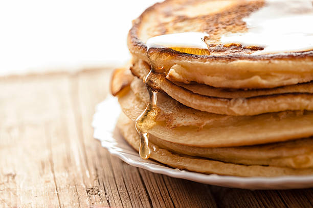 This is a photograph of a large tall stack of pancakes on a pink background
