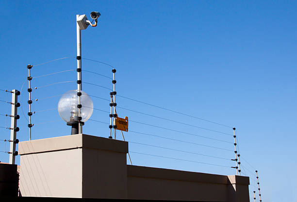 Electric Fence and Security Camera Atop Boundary Wall electric fence and security camera atop boundary wall enclosure stock pictures, royalty-free photos & images