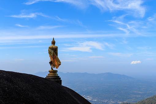 Image of buddha on the hill at khao khitchakut, clouds on the blue sky, Thailand.