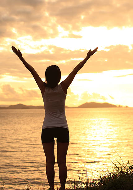 istock cheering woman open arms to sunrise seaside 487525145