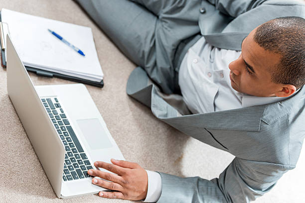istock African American businessman lying on floor and using laptop. 487526388