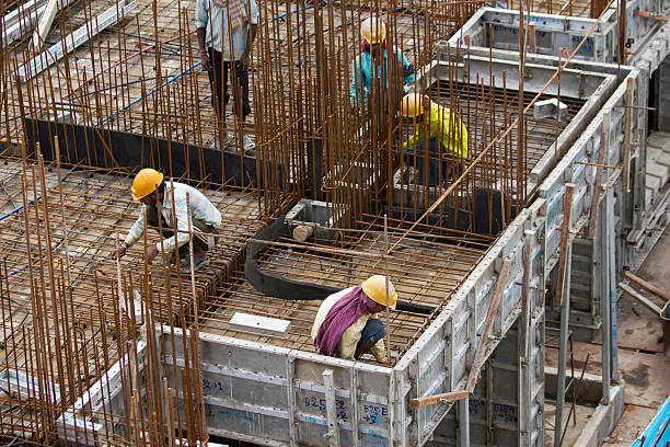 Mid adult female worker carrying bricks on head while working in building at construction site