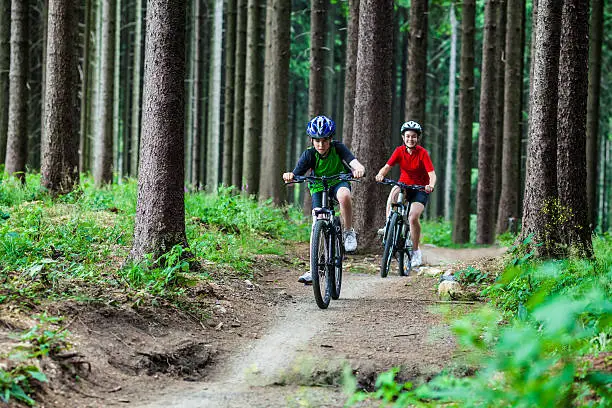 Photo of Teenage girl and boy biking on forest trails