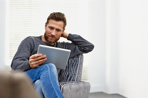 Young caucasian man at home using a tablet computer