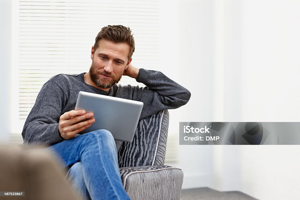 Young man at home using a tablet computer Young caucasian man at home using a tablet computer Digital Tablet Stock Photo