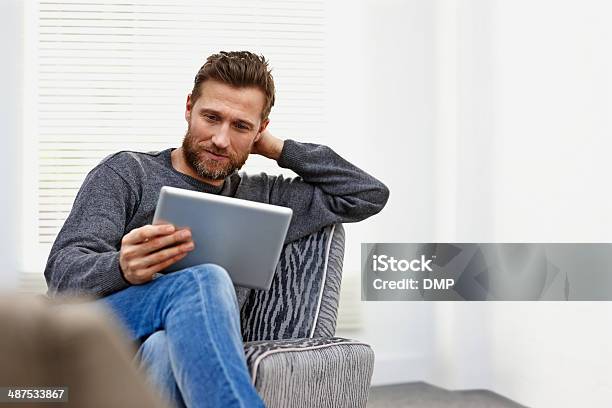 Young Man At Home Using A Tablet Computer Stock Photo - Download Image Now - Digital Tablet, Men, Reading