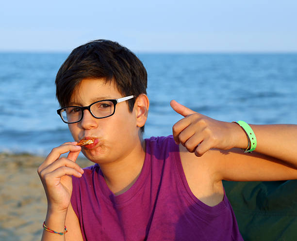 istock young boy OK sign with thumb up eating pizza 487538342