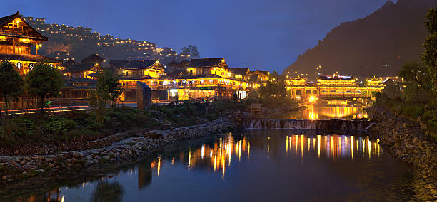 Xijiang miao village, Guizhou Province, China - april 18, 2010: Large the Miao ethnic minority village at night illuminated wooden buildings are reflected in the river night lights.