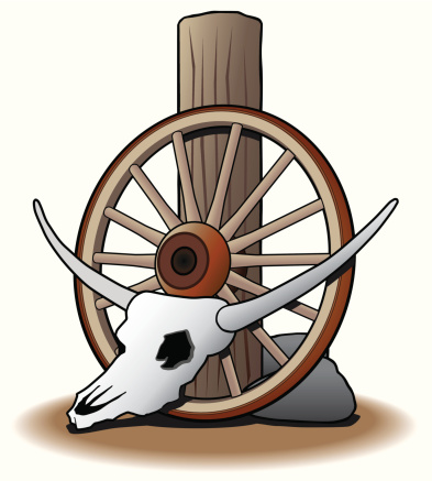 Steer skull in desert setting leaning against wagon wheel