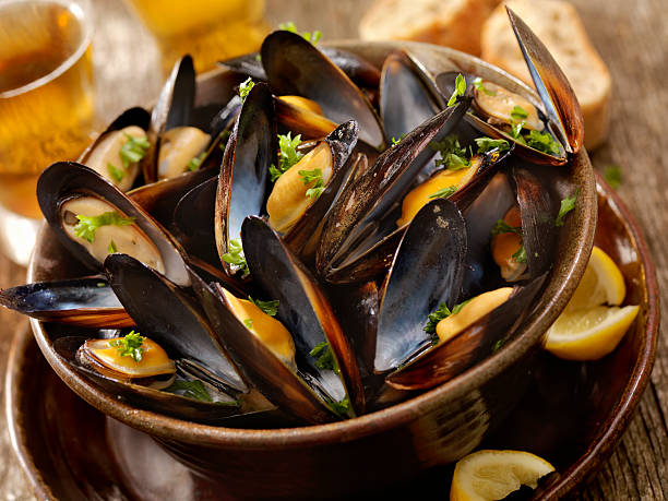 Steamed Mussels Steamed Mussels with Fresh Parsley, Bread and a Couple of Beers -Photographed on Hasselblad H3D2-39mb Camera steamed photos stock pictures, royalty-free photos & images
