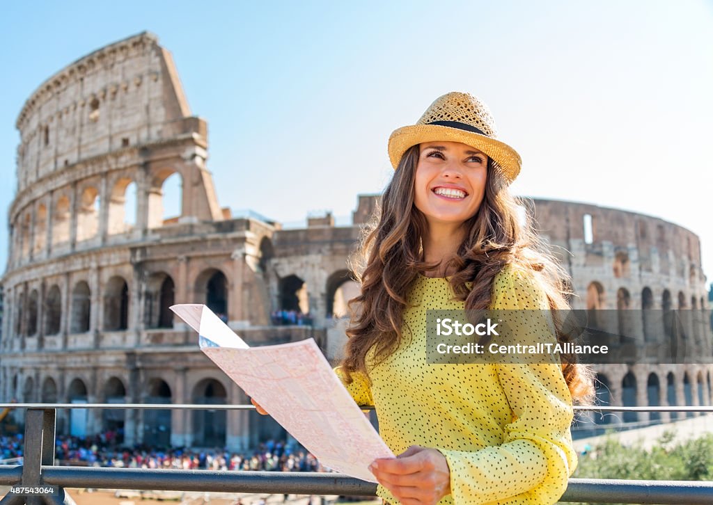 Happy woman tourist  at Rome Colosseum Woman is smiling and looking into the distance as she is holding a map of Rome. In the background, the Rome Colosseum and tourist crowds. Coliseum - Rome Stock Photo
