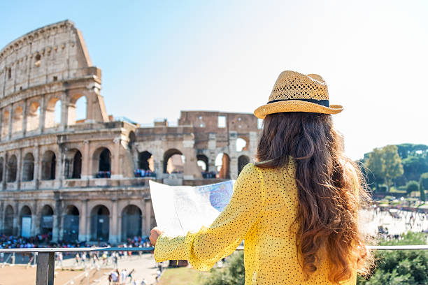 Woman tourist at Colosseum, Rome On hot summer's day, a woman is seen from behind and is holding a map of Rome. She is looking out onto Rome's Colosseum and the tourist crowds below. city break photos stock pictures, royalty-free photos & images