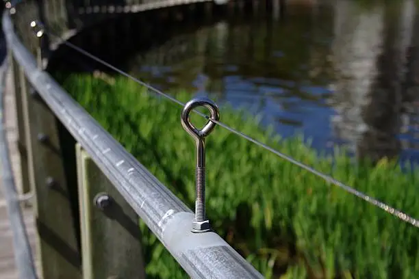 A handrail at a lake using a Stainless Steel Eyebolt and wire in the morning sun.