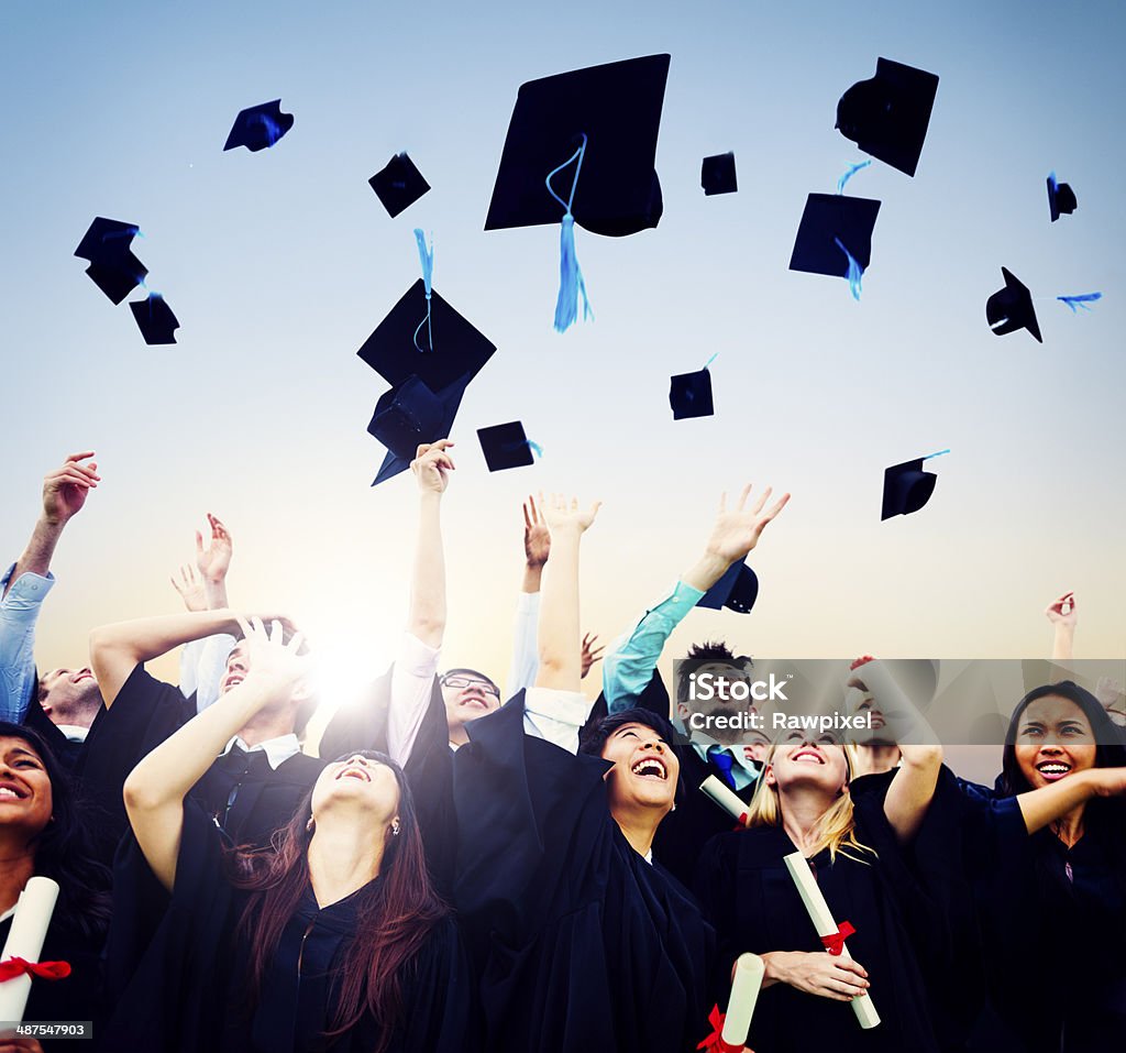 Smiling students throwing graduation caps in air A group of  graduates throwing their graduation caps into the air.  They are smiling and cheering as they look up at the hats. Graduation Stock Photo