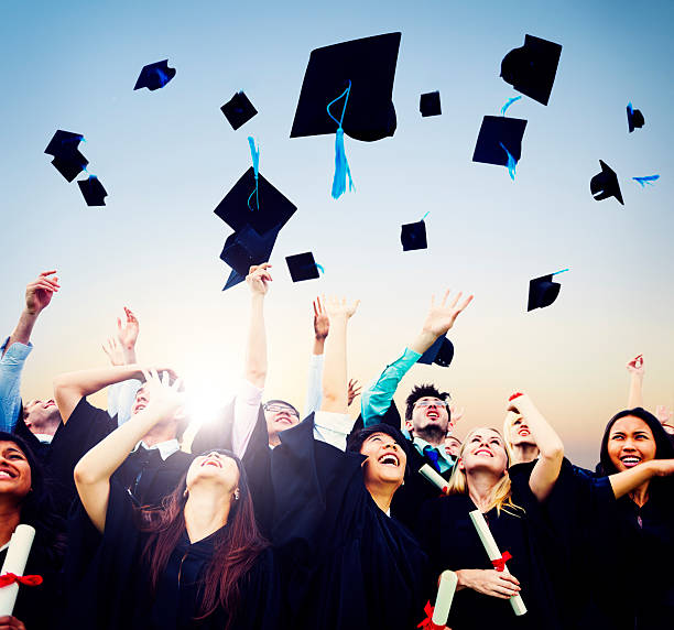 Smiling students throwing graduation caps in air A group of  graduates throwing their graduation caps into the air.  They are smiling and cheering as they look up at the hats. alumni stock pictures, royalty-free photos & images