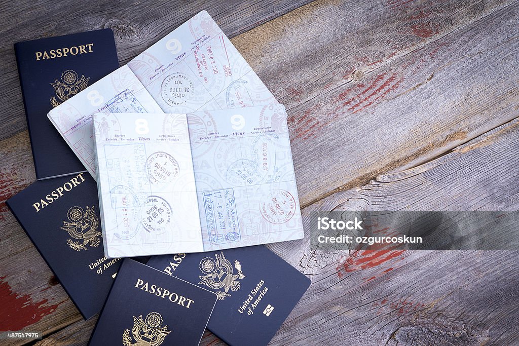 American passports open to reveal stamps American passports lying on a rustic wooden table open to reveal hand stamps from customs officials on border control applied during traveling abroad Passport Stock Photo