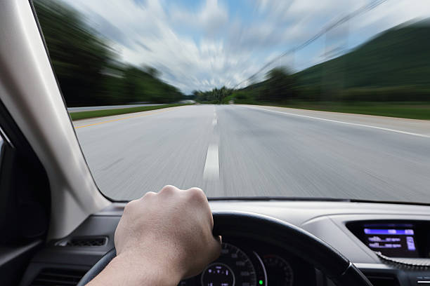 istock hand driving a car with speed on the street 487549264
