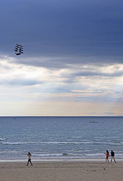 Bali, Indonesia - April 30, 2015: people are playing with the kite in the shape of ship on the seacoast of Bali, Indonesia