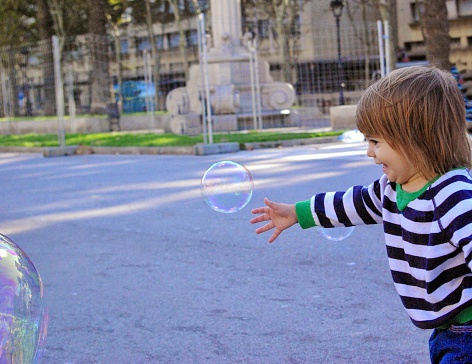 Little girl tries to catch a bubble in Barcelona, Spain