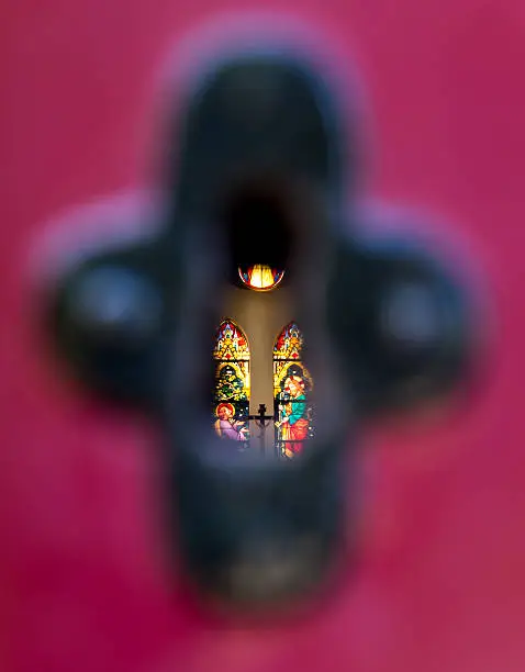 Peeking through keyhole in churchdoor. Seeing stained glass windows inside.